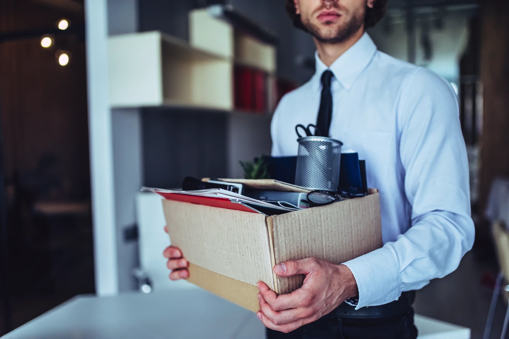 A Man Who Was Recently Fired Holding A Box Of Items From A Desk