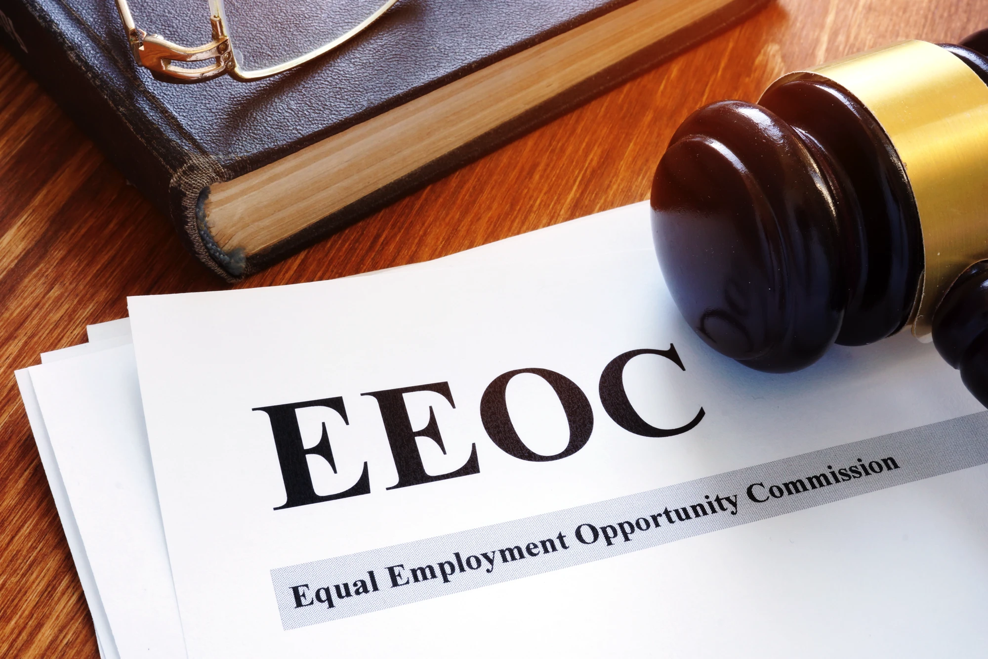 Papers That Say EEOC And A Gavel On A Desk Glasses And A Book Are Also In The Background On The Desk