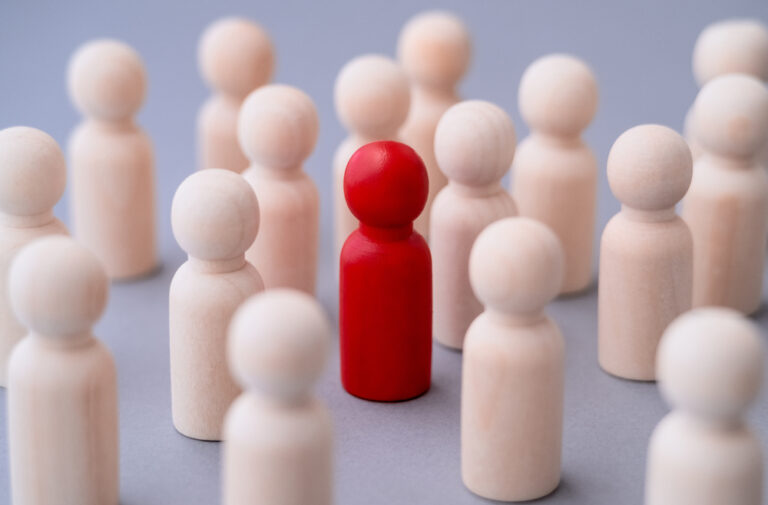 A set of pegs meant to represent people, with one red peg representing discrimination