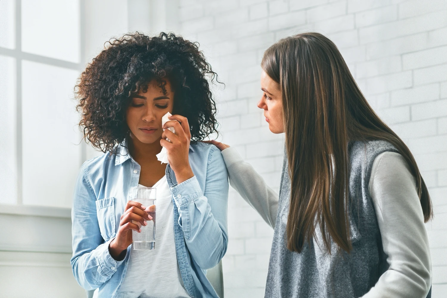 A coworker comforting another coworker who is crying