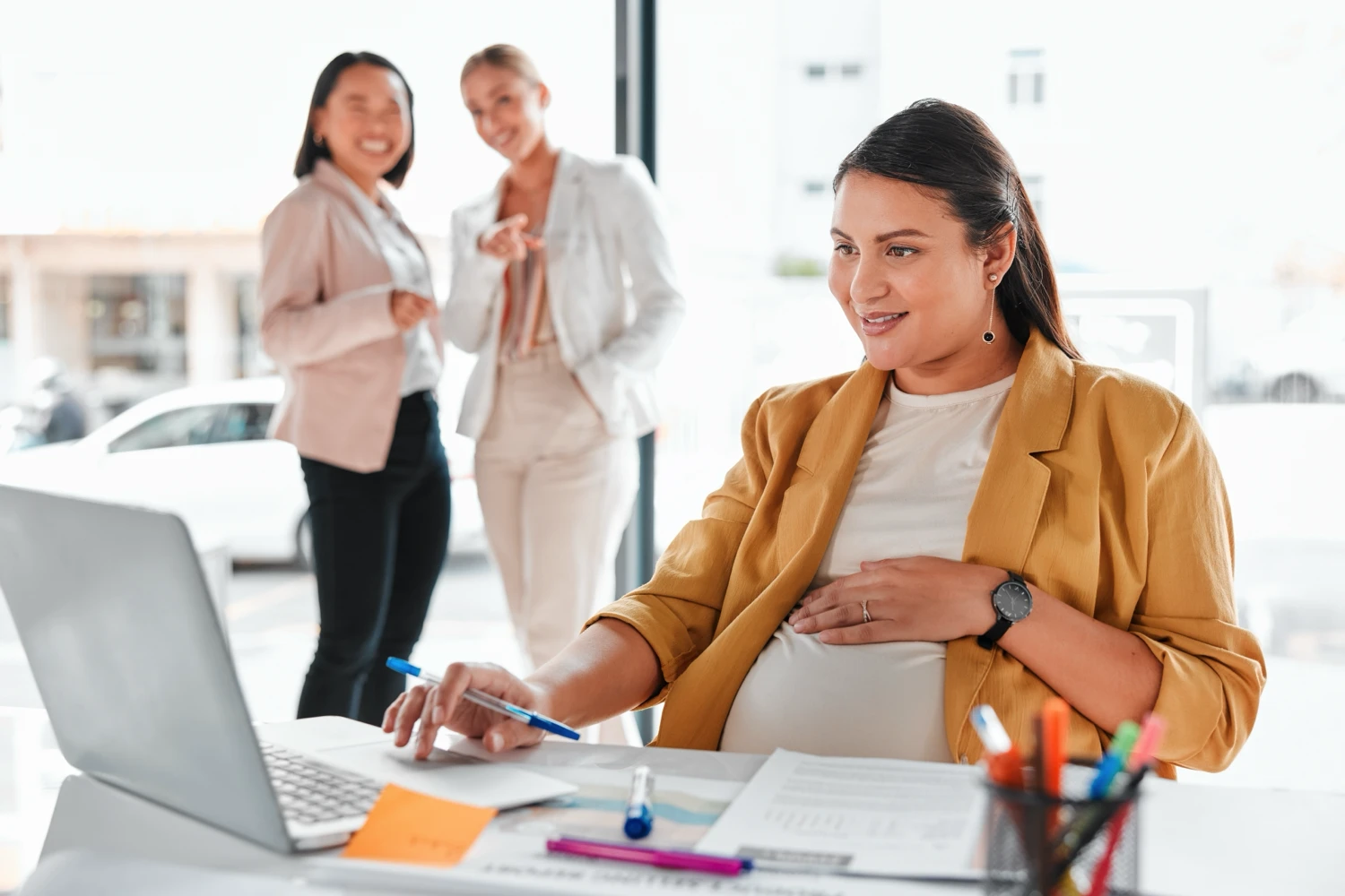 Coworkers gossiping about a pregnant worker in the office
