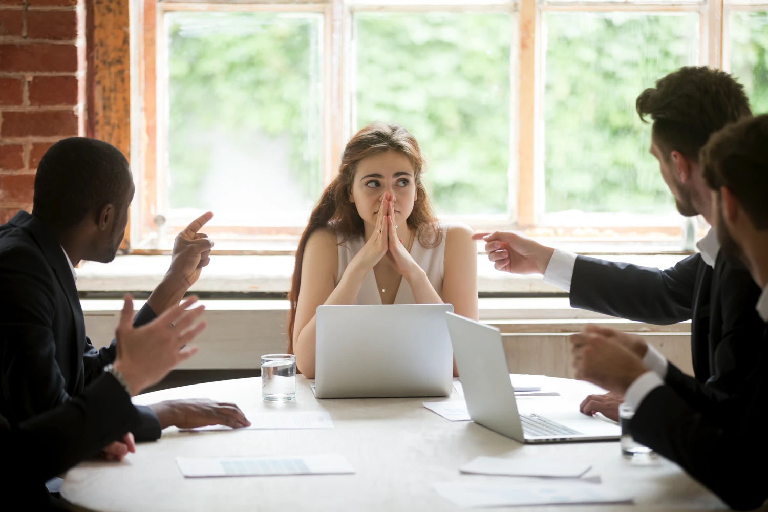 Young woman facing discrimination from her coworkers during a meeting